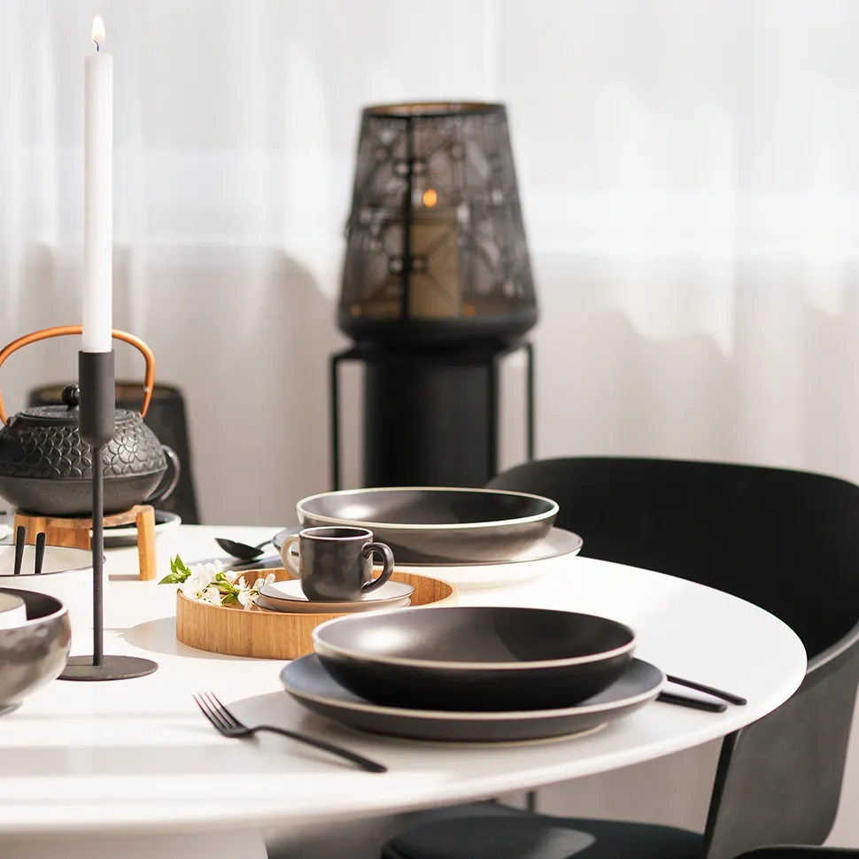 Pogrnjena miza s črnim porcelanom, čajnikom in svetilko